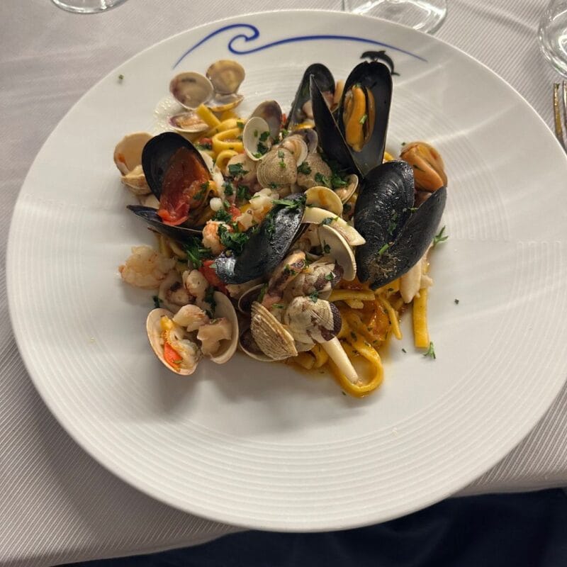 Plate of fresh pasta with mussels, clams, shrimp, and herbs at an Italian restaurant